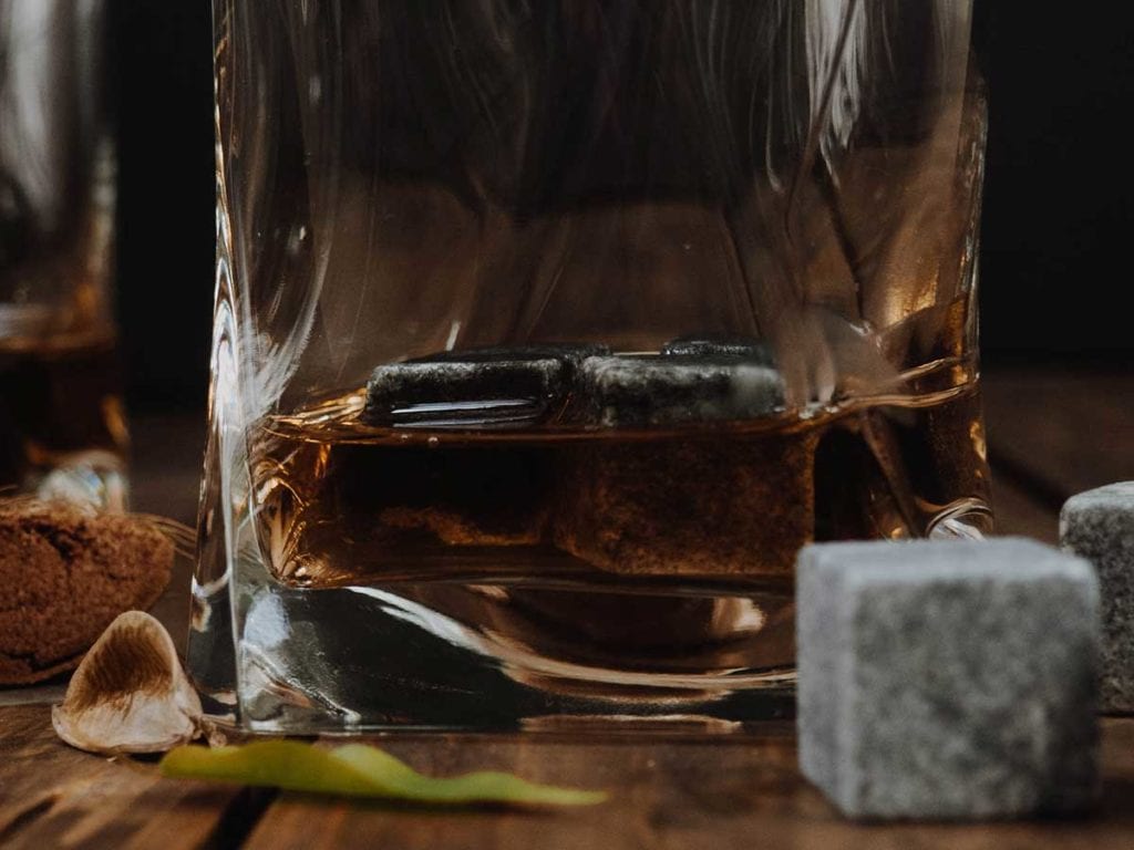 Soapstone whisky rocks in the glass covered with whiskey or bourbon 